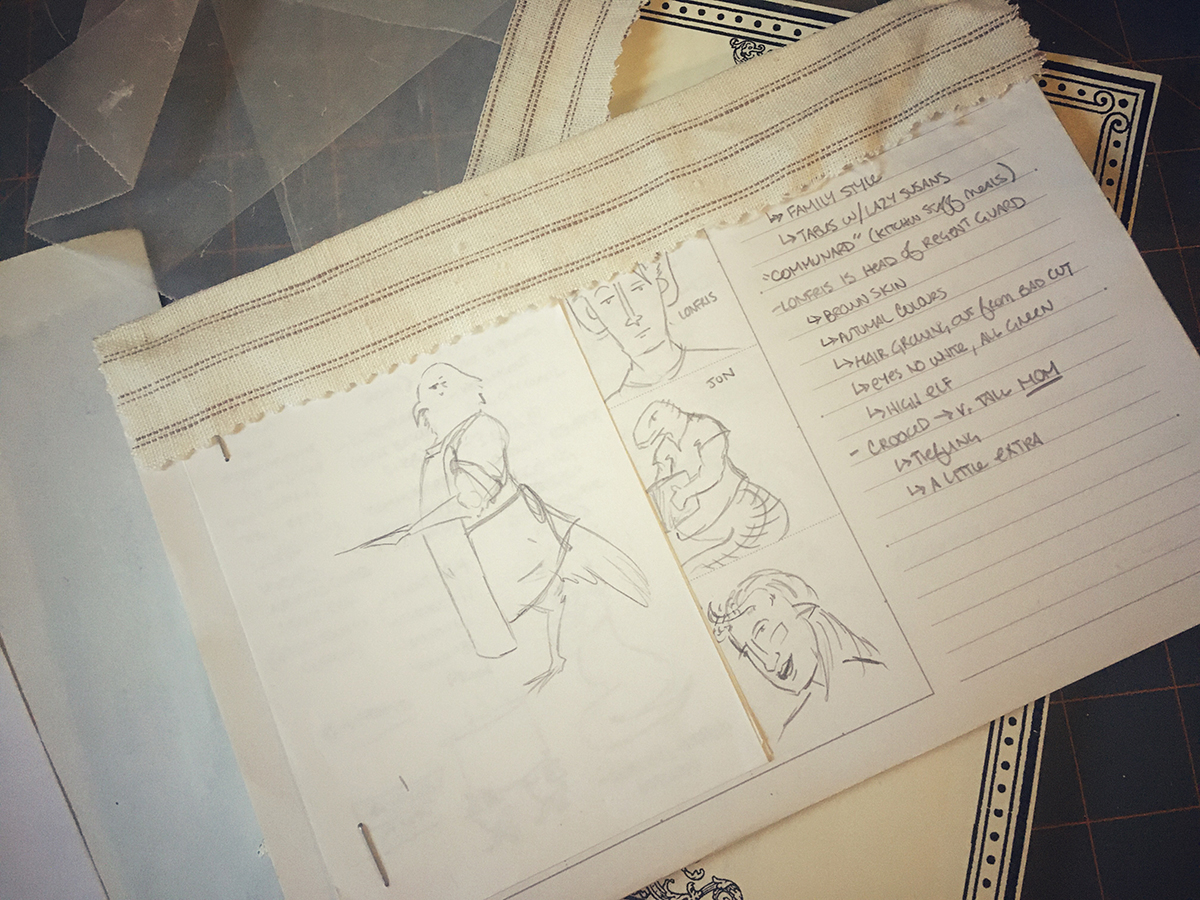 Two bound text blocks stacked on top of each other, the fabric covering the spine on both is a rough off-white weave with thin brown stripes. The top textblock's first page is a half-sketch and half-lined page scribbled with notes and character drawings, and has a separate small page stapled to it with a sketch of a bird wearing an apron.