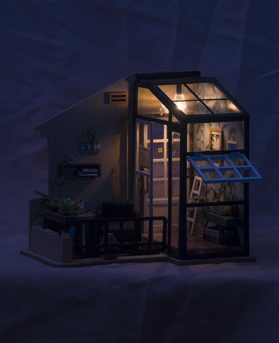 A wider view of the partial dollhouse previously described, this time the light evokes deep night, in a city area where there is always an ambient glow from streetlights. The light in the atrium is on, casting a clear and comparatively warm glow.