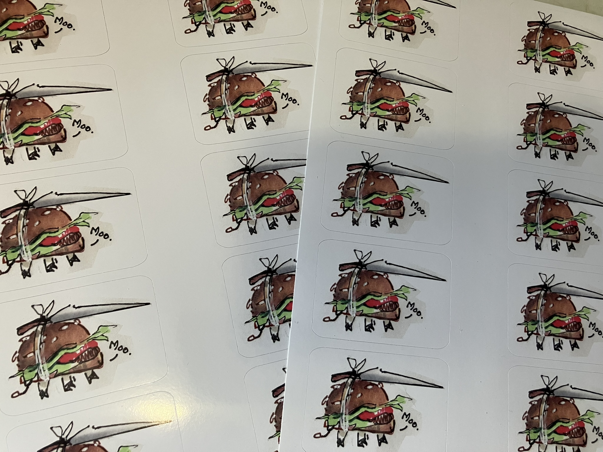 a photo of the uncut sticker sheet of moo-burgers. money was tight this month so i cut them myself!